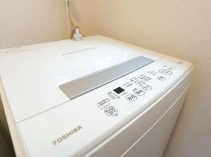 eine weiße Waschmaschine neben einer Wand in der Unterkunft F House Os Residence S2 in Osaka