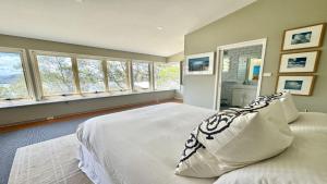 a bedroom with a large white bed with windows at 'Pretty Beach Escape' by HolidayCo in Pretty Beach