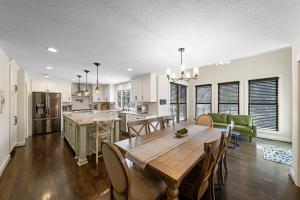 a kitchen and living room with a wooden table and chairs at EPIC Group Stay Big Gameroom Bar Arcade Playroom in Olathe