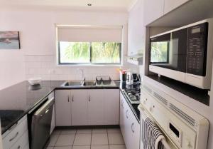 a white kitchen with a sink and a microwave at 5 36 Maurice Avenue in Mallacoota