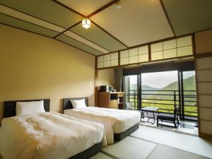 a hotel room with two beds and a balcony at Hakone Kowakien Mikawaya Ryokan in Hakone