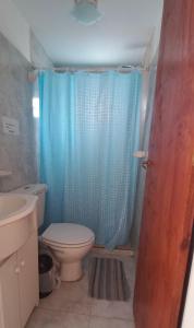 ein Bad mit einem WC und einem blauen Duschvorhang in der Unterkunft Jeleta 1 in Puerto Madryn