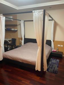 - une chambre avec un lit avec des rideaux et un bureau dans l'établissement Royal Apart Residence, à Phuket