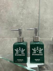two green bottles of soap sitting next to each other at Đầm Sen Homestay Retreat in Hòa Lạc
