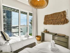 Cette chambre blanche dispose de deux lits et d'une fenêtre. dans l'établissement Ultra-Luxury 2 Bedroom Beachfront Escape with Sea Views, à Dubaï 65 autres photos