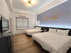 a bedroom with two beds and a tv in it at 翹班旅行民宿 in Magong