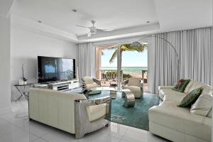 a living room with white furniture and a television and the ocean at White House - Exclusive Luxury Beachfront Villa - Private White Sand Beach in Nassau