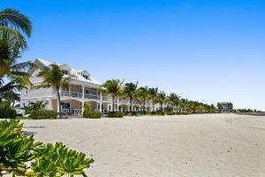 a row of houses on the beach with palm trees at White House - Exclusive Luxury Beachfront Villa - Private White Sand Beach in Nassau