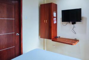 a bedroom with a cabinet with a tv on the wall at RedDoorz at Alejandro's Suites & Venue in Valencia +10 photos
