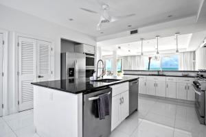a kitchen with white cabinets and a black counter top at White House - Exclusive Luxury Beachfront Villa - Private White Sand Beach in Nassau