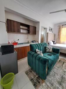 a living room with a green couch and a kitchen at Phoina Homes in Mombasa