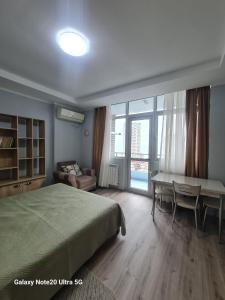 a bedroom with a bed and a desk and a table at Yalcin Star Residence Apartment 300 in Batumi