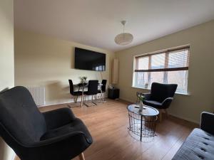 a living room with chairs and a table and a tv at Misk Homes #2 Near Heathrow Airport, shops & Brunel University - Free Parking in Uxbridge