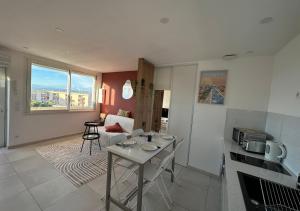 a kitchen and living room with a table and a couch at Le Studio Terracotta - Central & Lumineux in Palavas-les-Flots