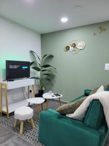 ein Wohnzimmer mit einem grünen Sofa und einem Fernseher in der Unterkunft Casa Bella - Borne arcade, Baby-Foot, Extérieur in Thiers + 23 Fotos