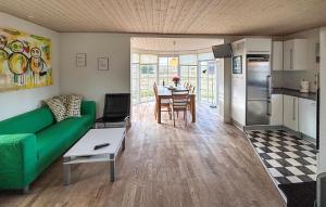 a living room with a green couch and a kitchen at Holiday Home Syrenvej Skjern Iii in Skjern