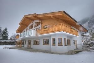 a house with a wooden roof in the snow at Chalet Apartment Ski and Golf by Kaprun Rentals in Zell am See