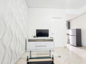 Una sala de estar con un televisor en una pared blanca. en Comfort Stay 1BR at Podomoro City Deli Medan Apartment By Travelio, en Medan