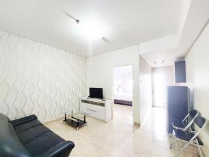 Una sala de estar con un sofá, un televisor y una cama. en Comfort Stay 1BR at Podomoro City Deli Medan Apartment By Travelio, en Medan 10 fotos más