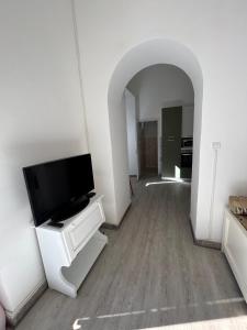 un salon avec une télévision à écran plat sur un meuble blanc dans l'établissement Villa Bonaccorso - antica e maestosa villa con piscina ai piedi dell'Etna, à Viagrande