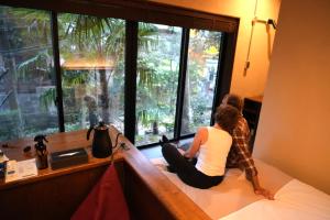 two people sitting on a bed looking out of a window at RoheN HAKONEYUMOTO in Hakone