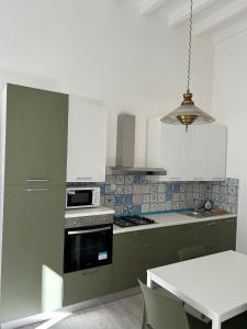 une cuisine avec des armoires vertes et une cuisinière four supérieur dans l'établissement Villa Bonaccorso - antica e maestosa villa con piscina ai piedi dell'Etna, à Viagrande