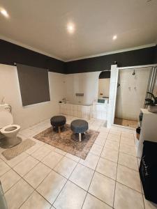 a bathroom with a toilet and two stools in it at Farm Apartment in Stampriet