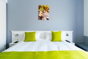 a bedroom with a white bed with green pillows at Hôtel Marso in Amnéville