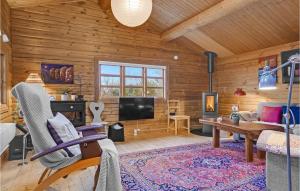 a living room with wooden walls and a flat screen tv at Cozy Log Cabin With A Panoramic View in Glesborg