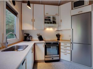 a kitchen with white cabinets and a stainless steel refrigerator at Hidden Gem With A Great View in Broager