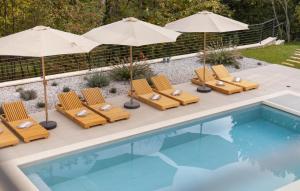 un groupe de chaises et de parasols à côté d'une piscine dans l'établissement Cozy Home In Icici With Sauna, à Ičići