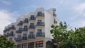 a tall white building with windows and trees at Mediterranea Residence in Salerno