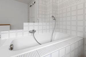 a white bath tub with a shower in a bathroom at Maison 9 personnes a Venthône, sauna et vue in Venthone +34 photos