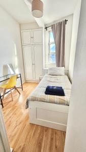 una camera da letto bianca con un letto e una scrivania di Single room near Bayswater close to tube & Bus a Londra