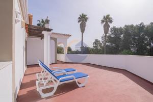 ein Paar Liegestühle auf einem Balkon mit Palmen in der Unterkunft Villa Suites Outdoor pool with golf view in Portimão