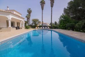 ein Swimmingpool vor einem Haus mit Palmen in der Unterkunft Villa Suites Outdoor pool with golf view in Portimão