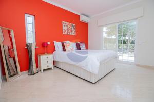 ein Schlafzimmer mit einer orangefarbenen Wand und einem Bett in der Unterkunft Villa Suites Outdoor pool with golf view in Portimão