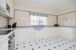 eine Küche mit weißen Schränken und einer Uhr an der Wand in der Unterkunft Villa Suites Outdoor pool with golf view in Portimão