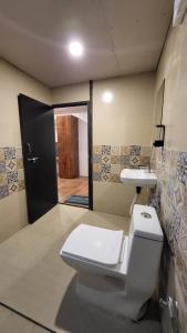 Un baño con inodoro, lavabo y puerta. en Nature Lovers Resort, en Indore