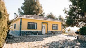 una casa gialla con un vialetto di ciottoli di Casa rural en Casas de Moya 'Casa del Pino Gori' a Casas de Moya