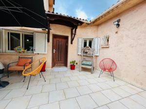 een patio met 2 stoelen en een huis bij Villa proche du centre-ville de Porto-vecchio et de ses plus belles plages in Porto-Vecchio