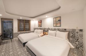 a hotel room with two beds and a desk at Laam Boutique Hotel in Da Lat