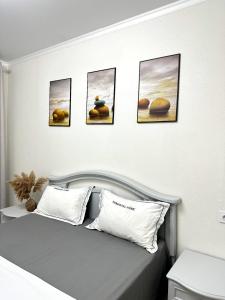 a bedroom with a bed with four pictures on the wall at 2х комнатная квартира с кодовым замком in Uralsk