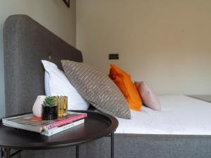 a bed with pillows and a table with books at Aura - Old Town I Free street parking I Self check-in in Bucharest