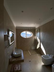 ein Badezimmer mit Waschbecken und Toilette und einem Fenster in der Unterkunft Hotel Eiffel in Tirana