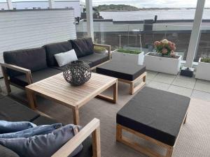 a patio with a couch and tables on a balcony at Waterfront apartment in Risør
