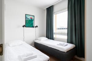 two beds in a room with a window at Hiisi Homes Kirkkonummi Masala Salmipolku in Masala