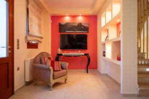 a hallway with a red wall with a chair and a desk at Villa Angels in Áno Kalésia