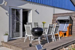 a grill on a deck with chairs and a table at Ferienhaus La Mer In Altefähr in Altefähr