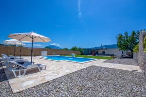a swimming pool with two chairs and an umbrella at Villa Elin in Seoca
